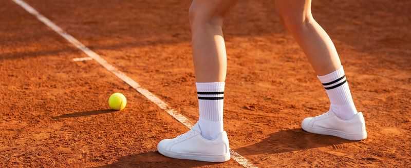A+ Bild: Tennissocken auf dem Sandplatz