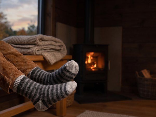 A+ Szene: Kind mit Ringelsocken am Kaminofen